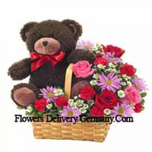 Ein schöner Korb aus roten und rosa Rosen, roten Nelken und anderen verschiedenen lila Blumen zusammen mit einem niedlichen 14 Zoll großen Teddybär